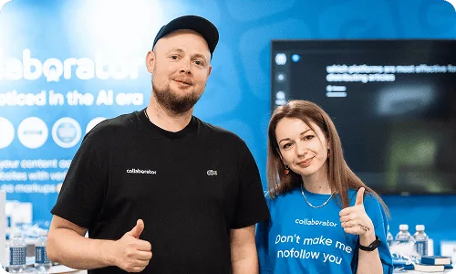 Два члена команды Collaborator позируют вместе у стенда на BrightonSEO 2026.