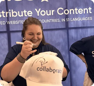 Член команды Collaborator кастомизирует брендированную кепку на стенде во время SEO Mastery Summit 2025.